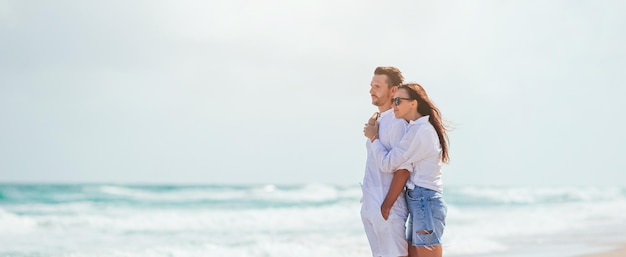 ビーチで恋をしている若いカップル 夏休み 幸せな男と女が海を見て