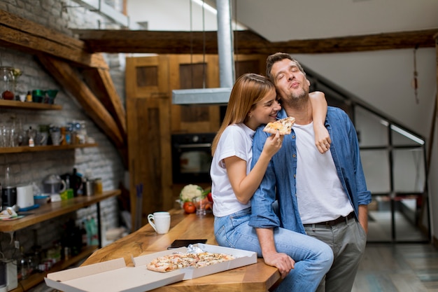 Giovane coppia in amore mangiando pizza in casa rustica