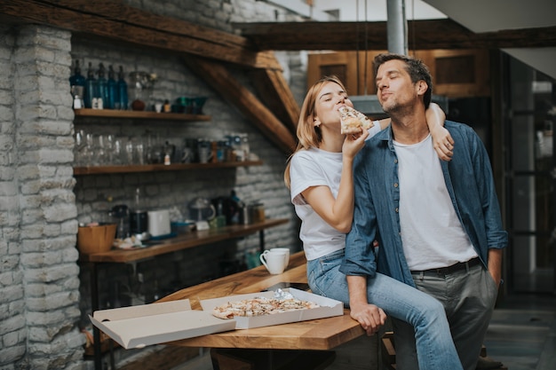 Young couple in love eating pizza in the rustic home