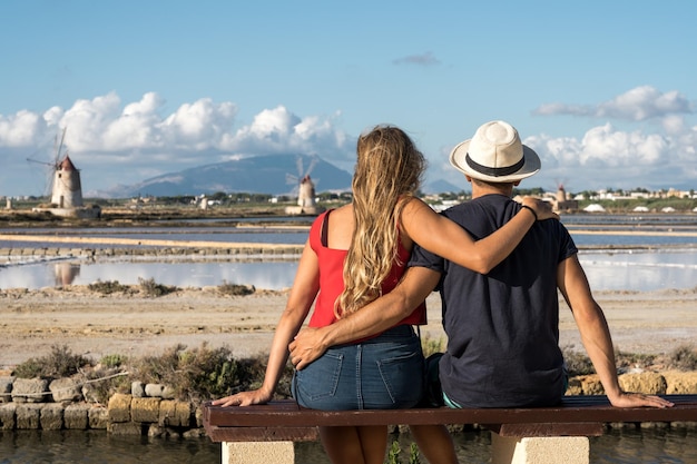 Young couple in love embracing contemplating the beauty of Salt flats in Sicily Italy