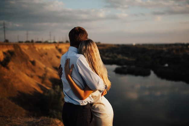 Giovani coppie nell'amore che godono della loro data sulla collina con il fiume