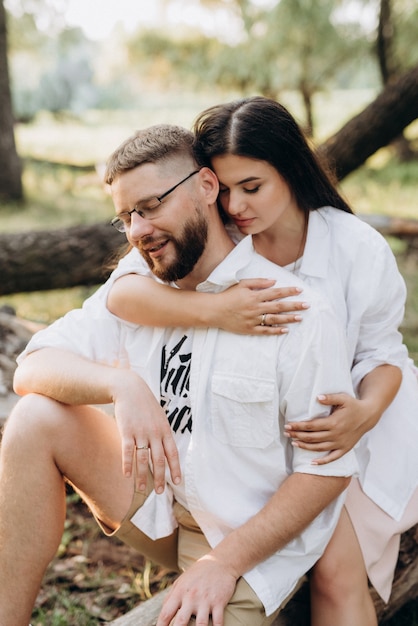 Giovane coppia innamorata di un ragazzo con la barba e una ragazza con i capelli scuri in abiti leggeri nella foresta verde green