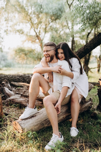 Young couple in love a guy with a beard and a girl with dark hair in light clothes in the green forest