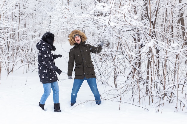 愛する若いカップルは雪に覆われた森で楽しんでいます。アクティブな冬休み。