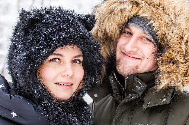 Young couple in love have fun in the snowy forest. Active winter holidays.