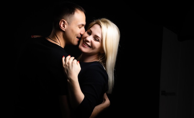 Young couple in love hug each other on the black background.