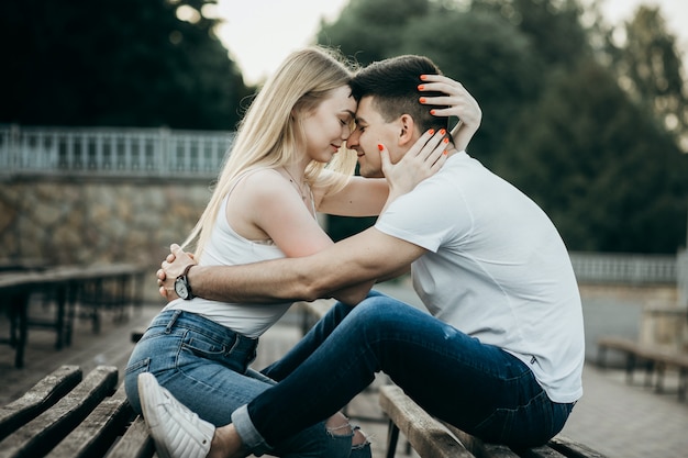 A young couple in love kissing on the bench in the park