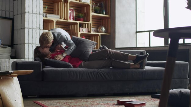 Young couple in love kissing on couch in living room