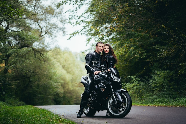 young couple in love on a motorcycle on the road in the woods