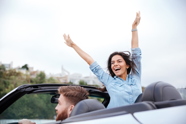 Young couple in love on road trip driving in convertible car