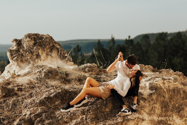 Young couple in love sitting on a stone overlooking and looking at each other the mountains