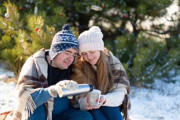 Young couple in love sitting in the winter in the forest