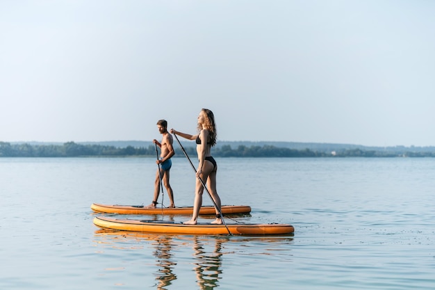 Young couple in love standing on their sapboards and holding each others hands