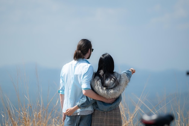 young couple in love on the top of the mountain with raised hands