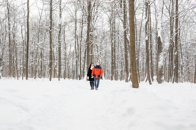 雪に覆われた森の中を歩くのが大好きな若いカップル。