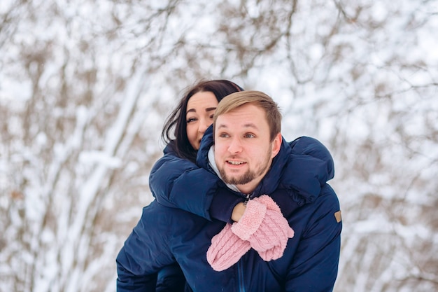 愛の若いカップルが冬の森を歩く、雪に覆われた森の中の男と女のポートレート、クローズアップ