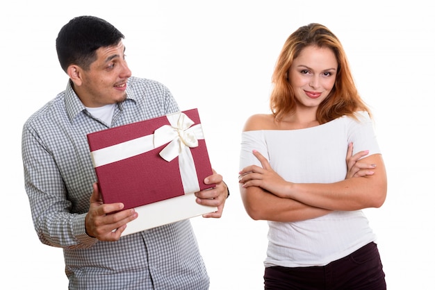 Young couple in love with man looking at woman while opening gift box looking surprised