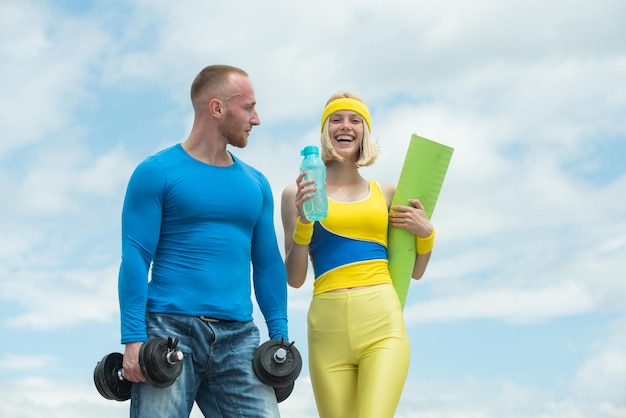 Молодая влюбленная пара тренируется на открытом воздухе, мускулистый спортивный тренер с веселой улыбающейся молодой женщиной