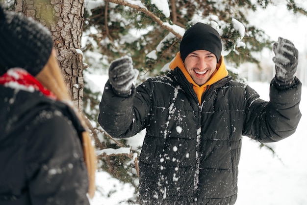 Young couple of lovers standing in the snow and having fun outdoors