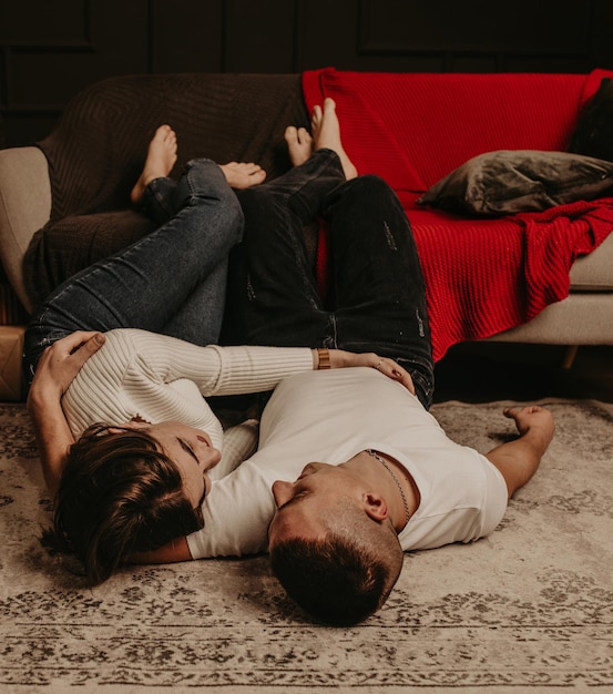 Photo young couple lying on floor at home