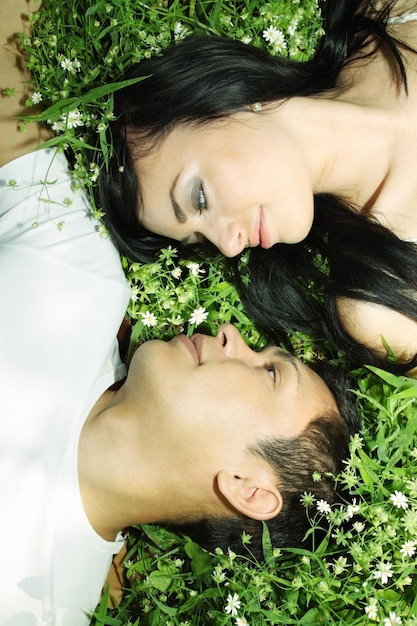 Young couple lying on grass face to face