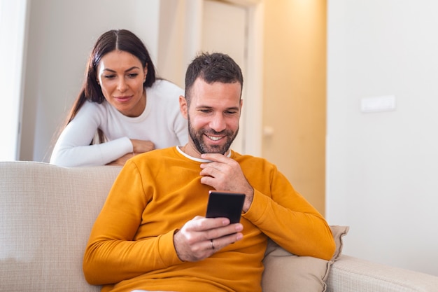 Young couple lying at home. One of them use the phone and flirting.