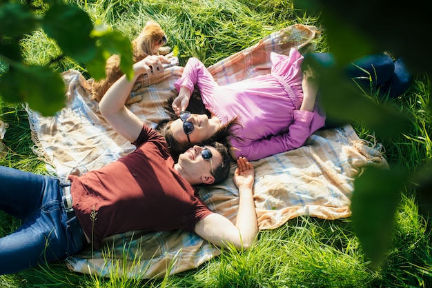 Young couple lying on lawn head to head in the park. Top view