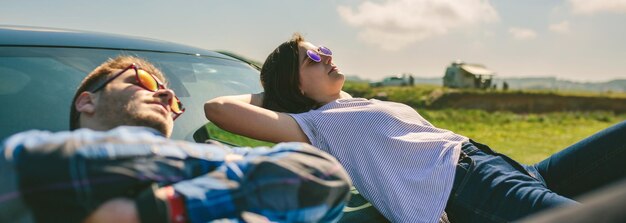 フロント ガラスに横になっている若いカップル