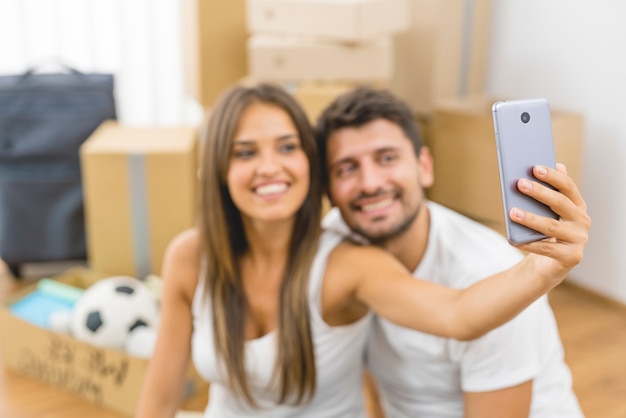 The young couple make a photo on the background of the carton boxes