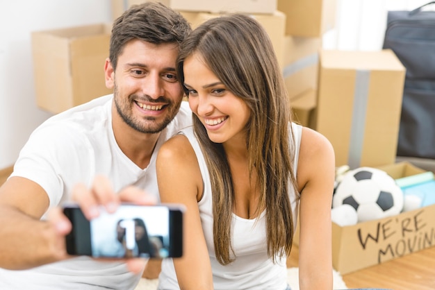 The young couple make a photo on the background of the carton boxes