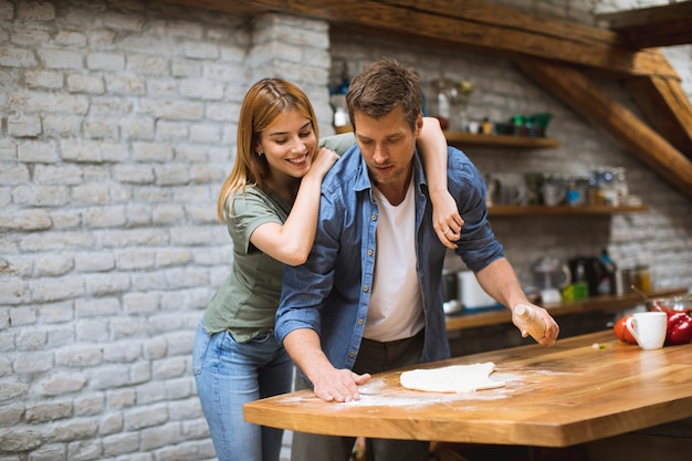 Photo young couple making pizza in rustic kitchen together