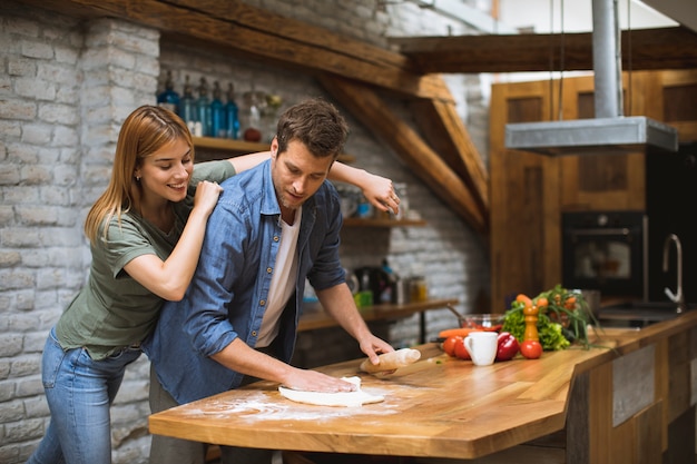 Young couple making pizza in rustic kitchen together