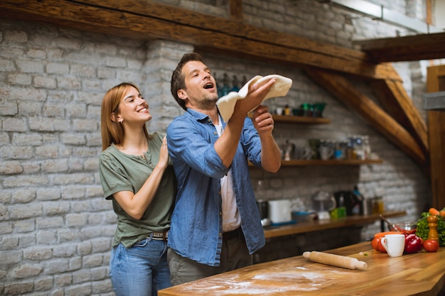 Young couple making pizza in rustic kitchen together