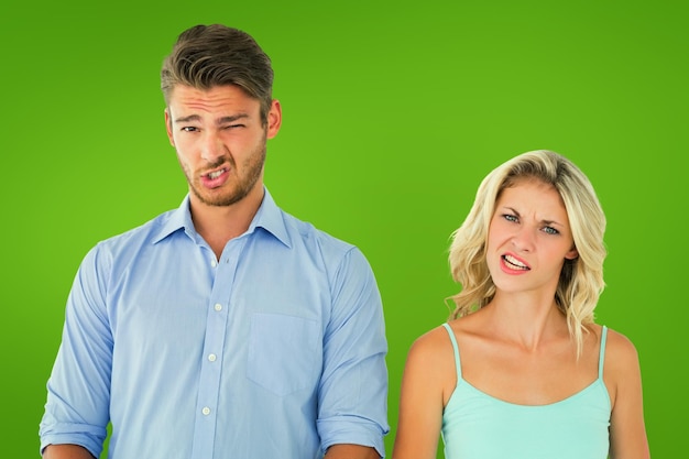 Young couple making silly faces against green vignette