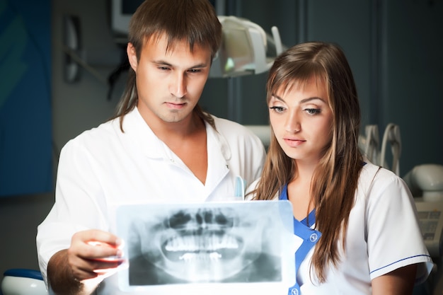 Coppia giovane uomo e donna in clinica dentale, guardando l'immagine dentale