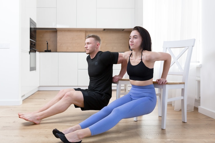young couple man and woman doing fitness together at home on the floor, two people doing sports exercises in the kitchen on a sports mat