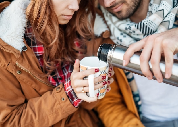 男性と女性の若いカップル、冬の日に熱いお茶を飲みます。