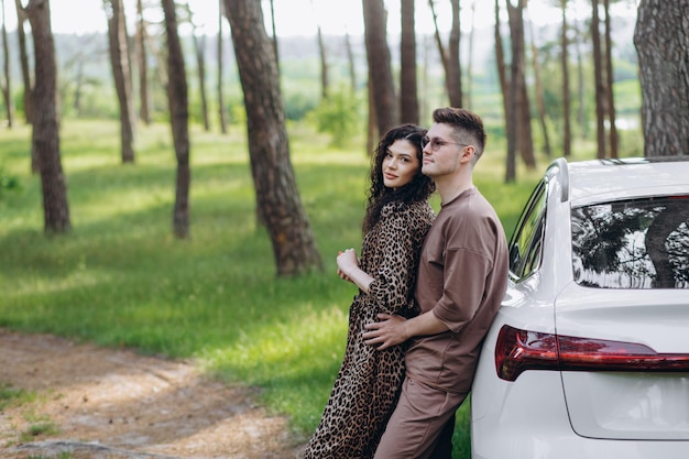 Young couple man and woman traveling together by new car having\
stop at charging station holding cups drinking hot coffee talking\
smiling happy while waiting vehicle to charge fully