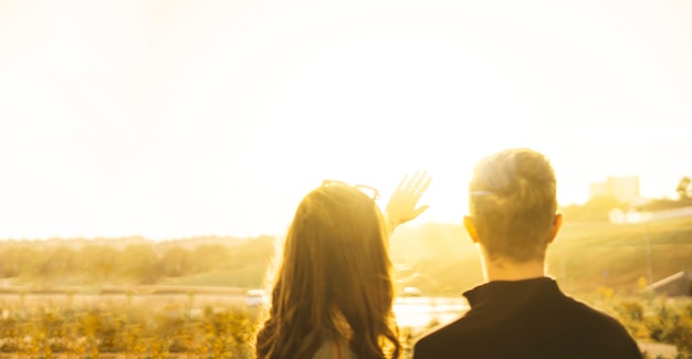 Foto una giovane coppia di uomo e donna che guarda il cielo e copre il sole con le mani, bellezza del raggio di sole