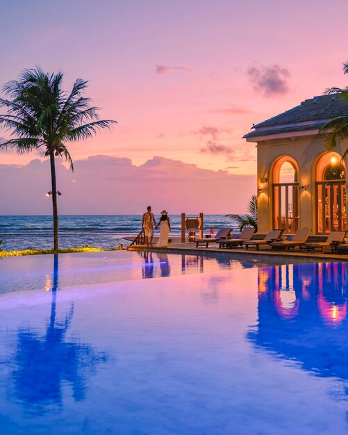 A young couple of men and women at a swimming pool during a vacation on a tropical island watching