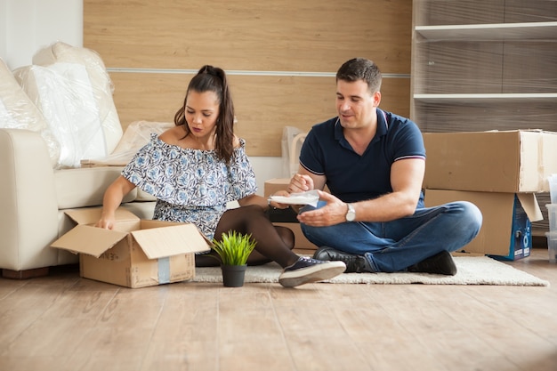 Young couple moving in a new home.Man and woman unboxing fragile stuff.