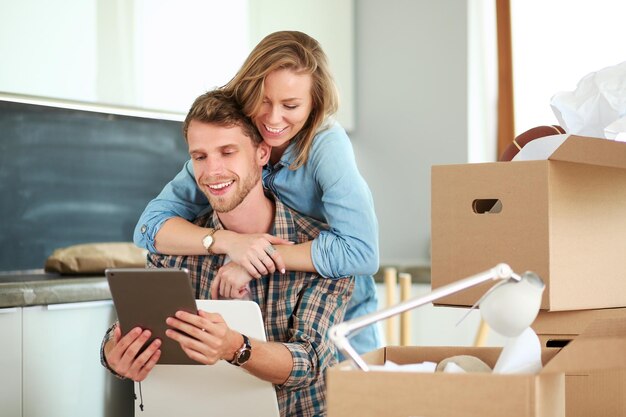 Young couple moving in new homeSitting and relaxing after unpackingLooking something on laptop Young couple