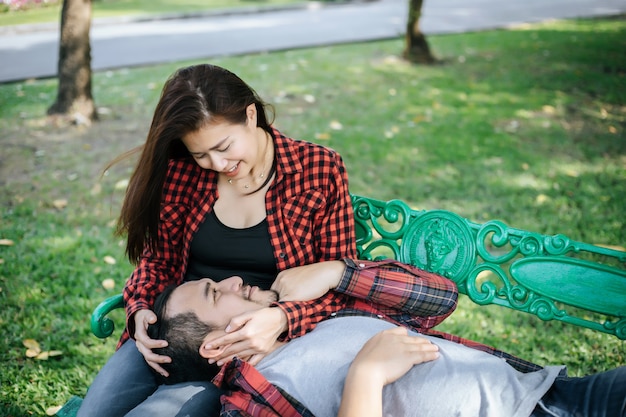 Young couple in nature sitting on bench, male and female together