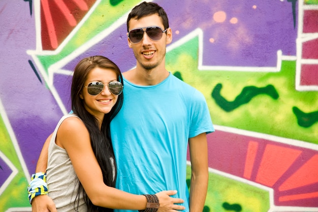 Молодая пара возле стены граффити.