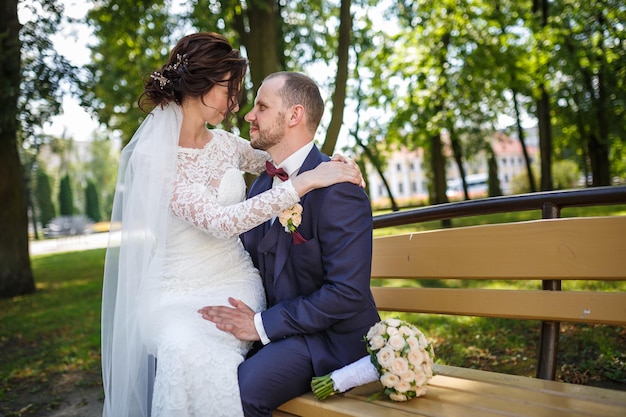 Young couple newlyweds kissing on a park bench