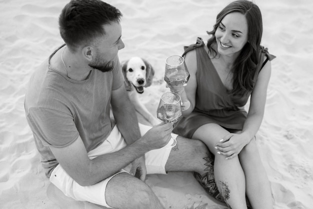 Young couple in orange clothes with dog in the desert white sands