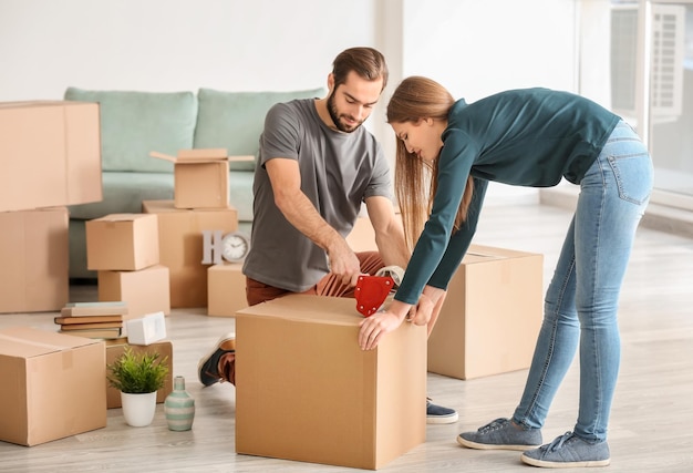 Young couple packing moving boxes indoors