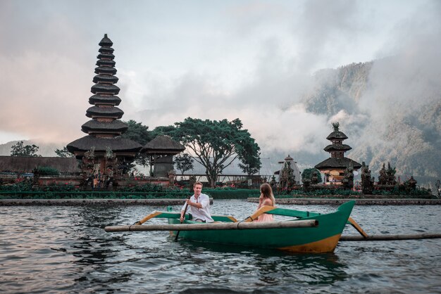 Foto giovani coppie che remano su una barca di legno a pura ulun danu bratan