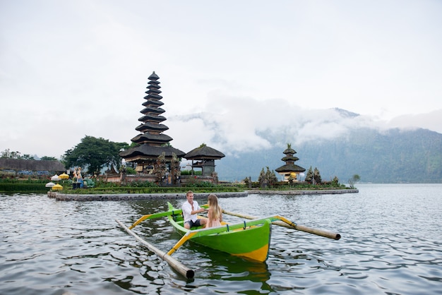 Pura Ulun Danu Bratan에서 나무 보트에 얕은 젊은 부부