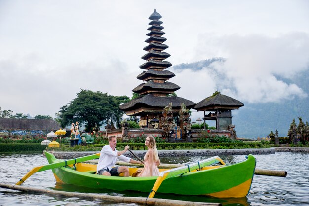 Pura Ulun Danu Bratan에서 나무 보트에 얕은 젊은 부부